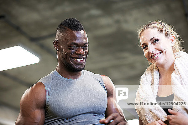 Trainer and female client laughing in gym