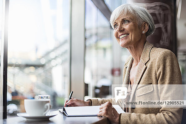 Smiling senior businesswoman taking notes in a cafe
