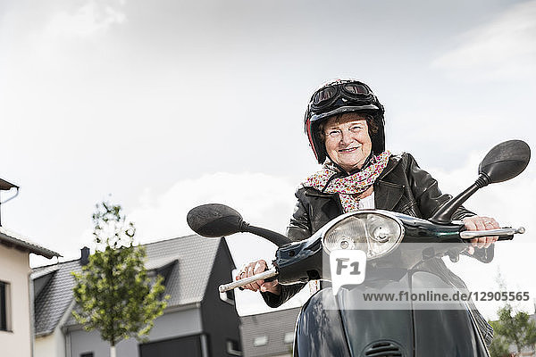 Active senior lady riding motor scooter in the city