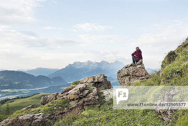 Austria  Tyrol  Fieberbrunn  Wildseeloder  woman sitting on stone with view on mountainscape