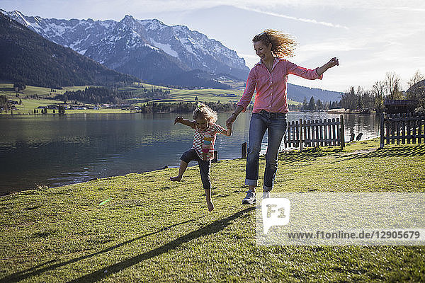 Austria  Tyrol  Walchsee  carefree mother and daughter jumping at the lake