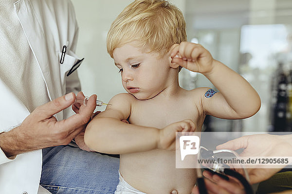 Pediatrician vaccinating toddler  injecting infant's arm