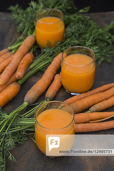 Three glasses of fresh carrot juice and carrots