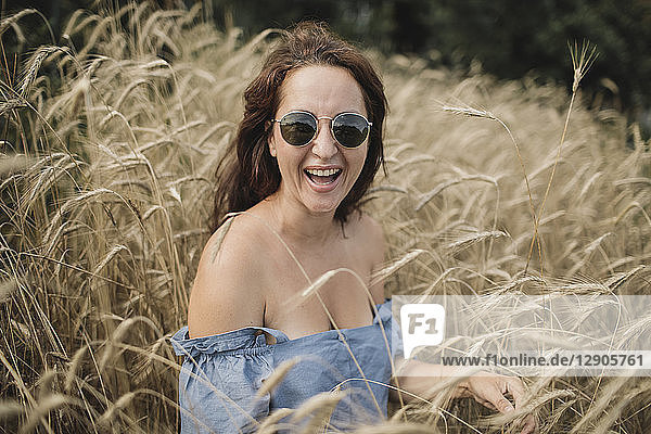 Portrait of happy woman wearing sunglasses in wheat field