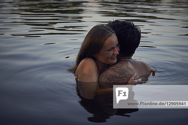 Romantic couple embracing in lake at sunset