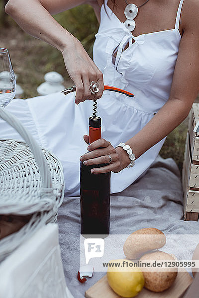 Woman opening bottle of wine at a picnic