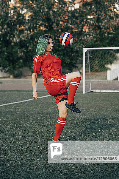 Young woman playing football on football ground balancing the ball