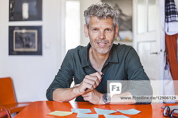 Portrait of mature man sitting at table with notepads