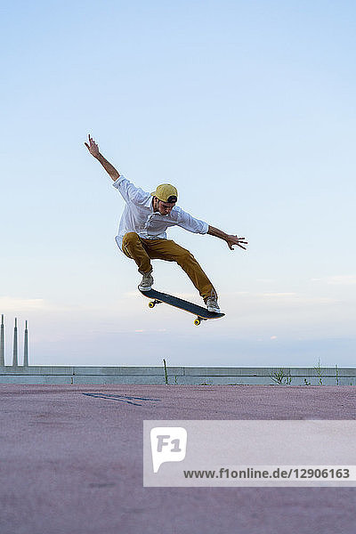 Young man doing a skateboard trick on a lane at dusk