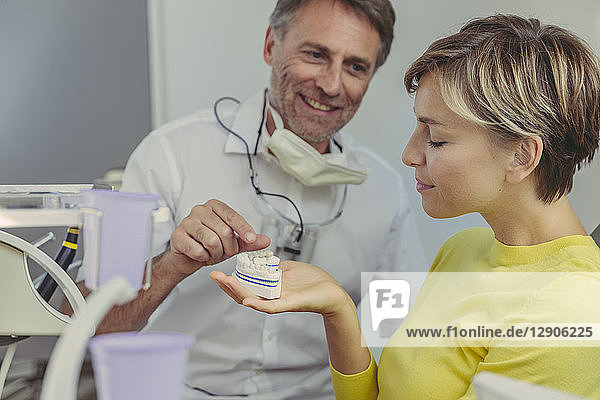 Dentist explaining dental bridg on a tooth model to his patient