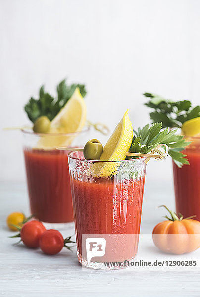 Glasses of fresh spicy tomato juice with cellery garnished with lemon slice  green olive and parsley