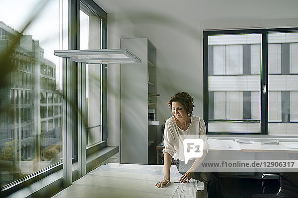 Businesswoman sitting in office  working on blueprints