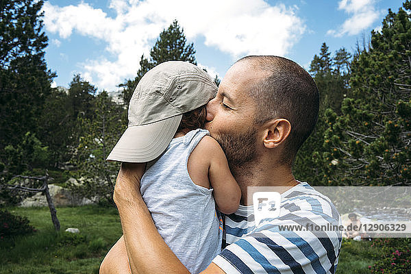Spain  Father hugging and kissing his little daughter in nature