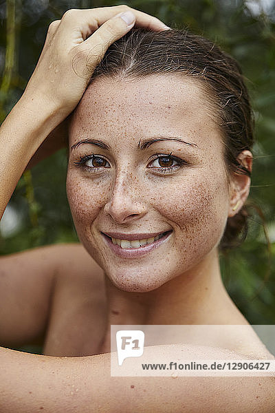 Portrait of smiling young woman with freckles in nature