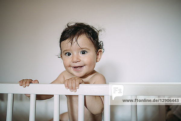 Portrait of happy baby girl in crib