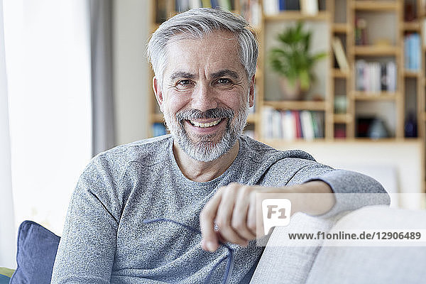 Portrait of smiling mature man sitting on couch at home