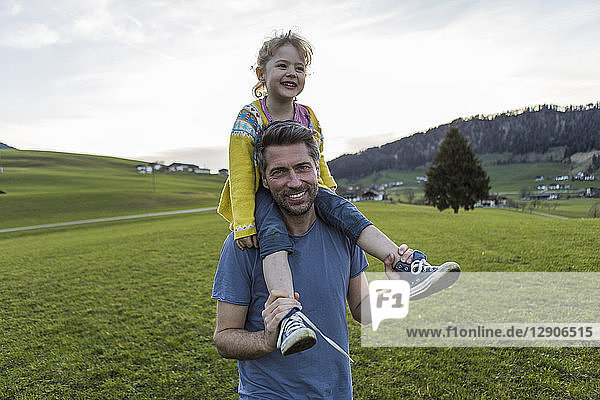 Austria  Tyrol  Walchsee  happy father carrying daughter piggyback on an alpine meadow