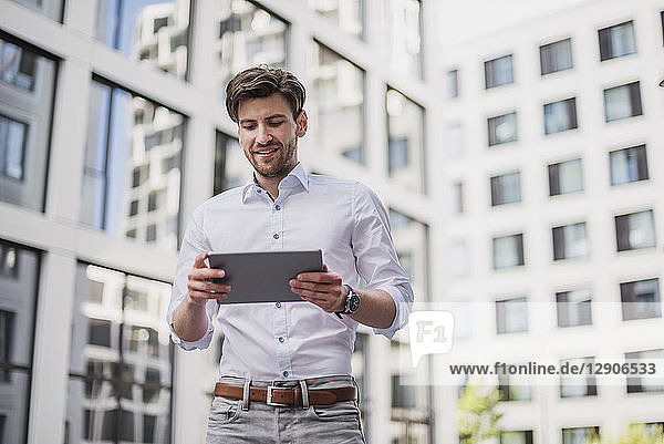 Smiling businessman in the city using tablet
