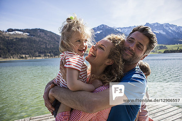 Austria  Tyrol  Walchsee  happy family hugging on a jetty at the lakeside