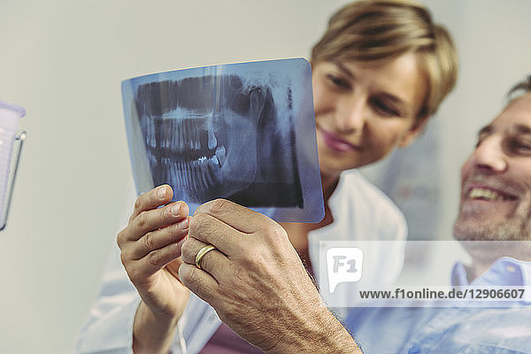 Dentist explaining x-ray image to smiling patient
