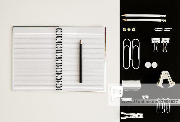 White office utensils on black background and notepad and pencil on whilte background