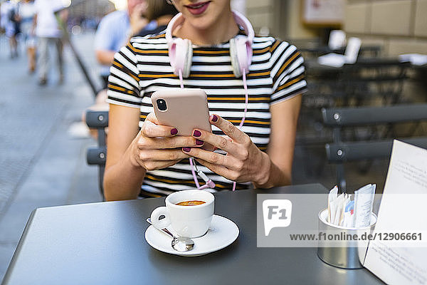 Young woman using smartphone at pavement cafe  partial view