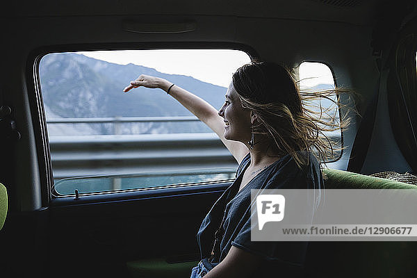 Happy young woman sitting on backseat in a car looking out of window