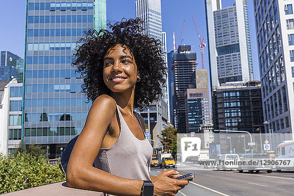 Germany  Frankfurt  portrait of smiling young woman with curly hair in the city