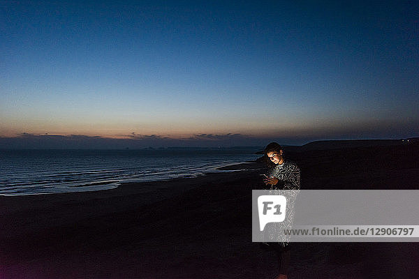 Young woman using smartphone on the beach at night
