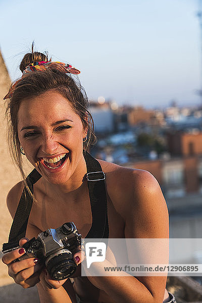 Laughing topless young woman with camera on balcony