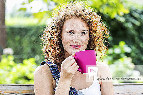 Portrait of redheaded young woman with pink coffee cup
