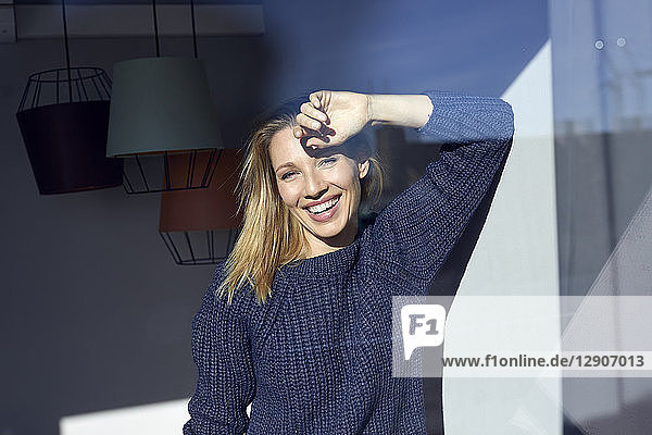 Portrait of laughing blond woman behind windowpane