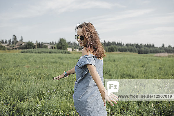 Smiling woman wearing sunglasses walking in rural field