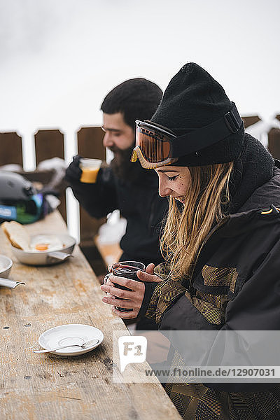 Couple in skiwear having a hot drink at mountain lodge