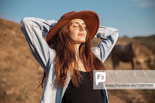 Young woman wearing a hat relaxing and enjoying the rural landscape