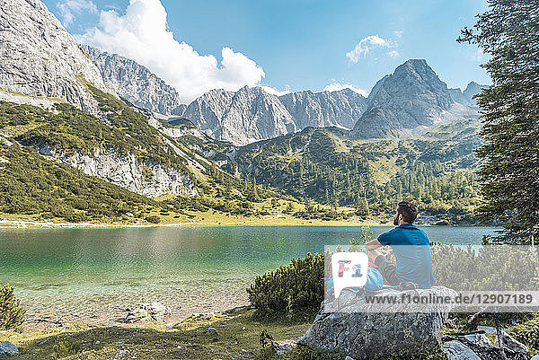 Austria  Tyrol  Hiker taking a break  sitting on a rock  looking at lake