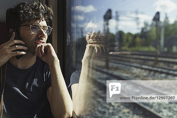 Man traveling by train talking on cell phone at the window