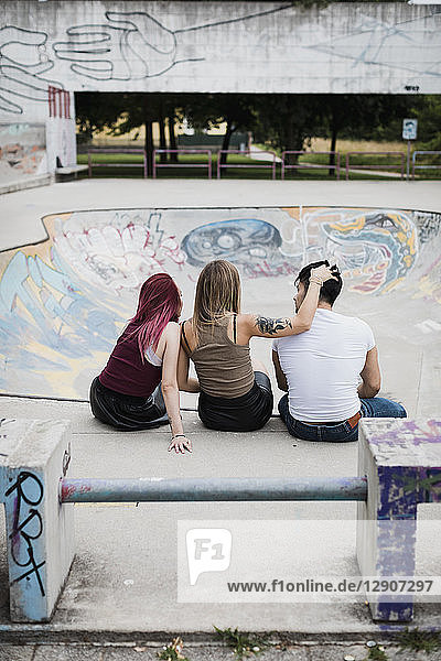 Rear view of friends sitting in skatepark