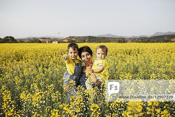 Spain  portrait of laughing mother with little son and daughter in a rape field