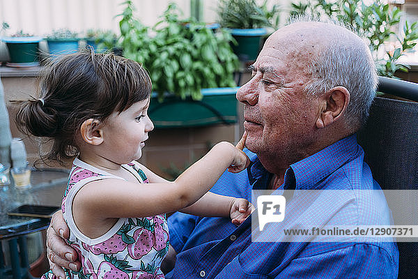 Grandfather and baby girl playing together on the terrace