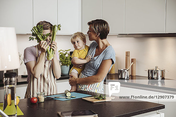 Playful lesbian couple and their child in kitchen