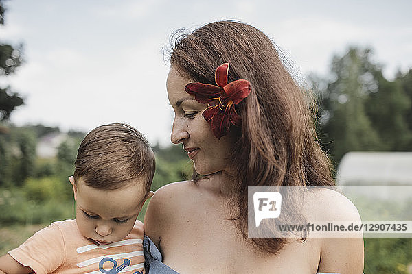 Mother with flower in her hair holding baby in garden