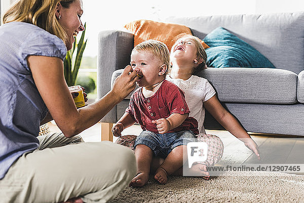 Mother feeding kids in living room