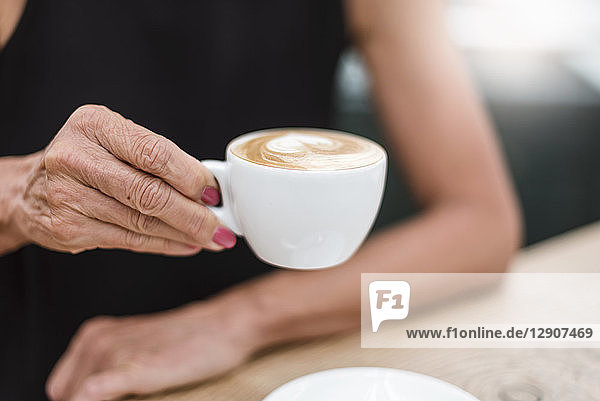 Close-up of senior woman holding a cup of cappuccino