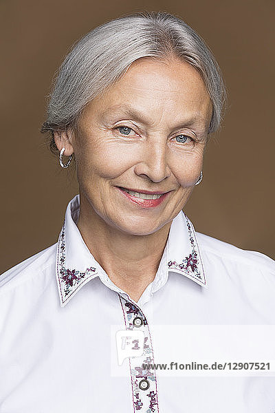 Portrait of smiling senior woman with grey hair wearing embroidered blouse
