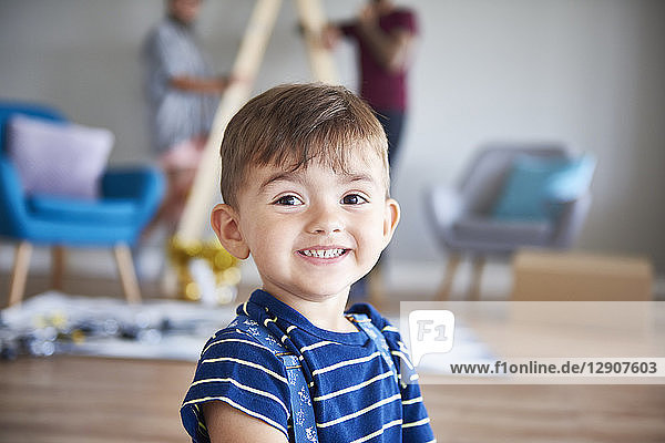 Portrait of smiling boy at home with parents in background