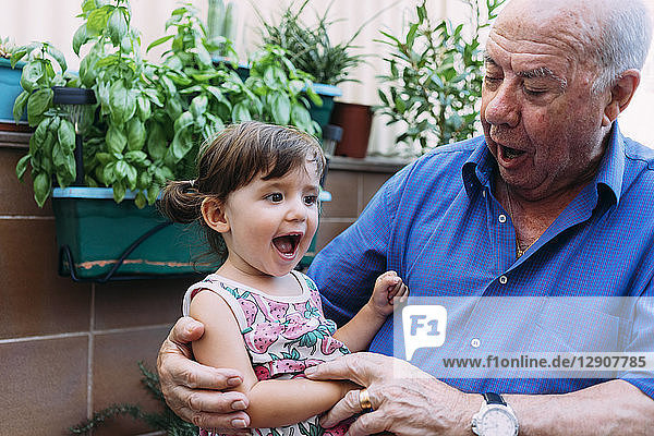 Grandfather and granddaughter singing together on the terrace