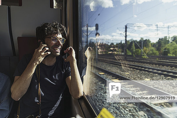 Happy man traveling by train talking on cell phone