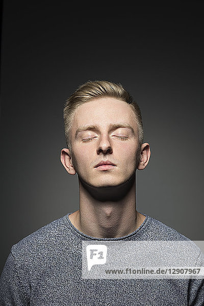 Portrait of blond young man with eyes closed