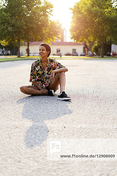 Smiling young woman sitting outdoors at sunset